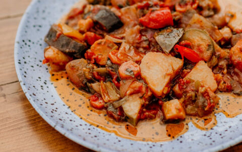Traditional Greek vegetable stew served on a plate at a seaside table in Stoupa