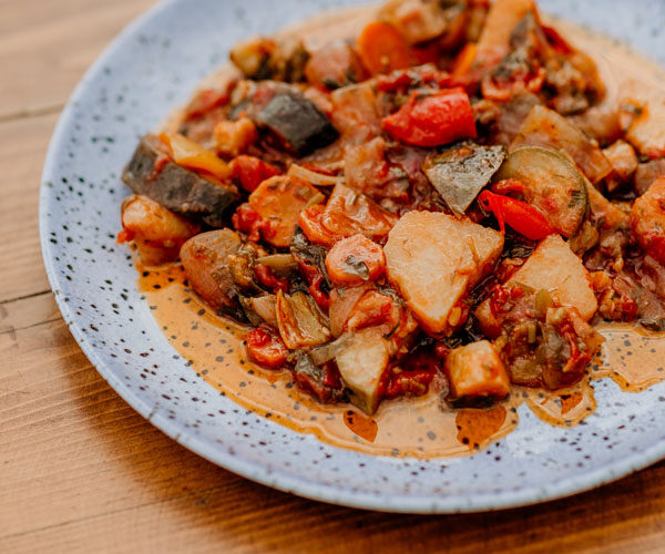 Traditional Greek vegetable stew served on a plate at a seaside table in Stoupa