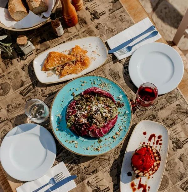 Meze plates, bread and wine on the terrace table at Liastres restaurant in Stoupa