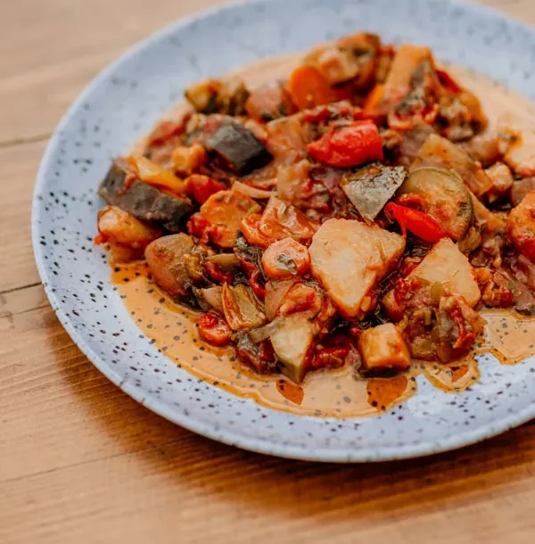 Traditional Greek vegetable stew served on a plate at a seaside table in Stoupa